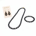Black beaded necklace and earrings on a white background