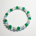 Beaded bracelet with green, white, and blue beads on a light background