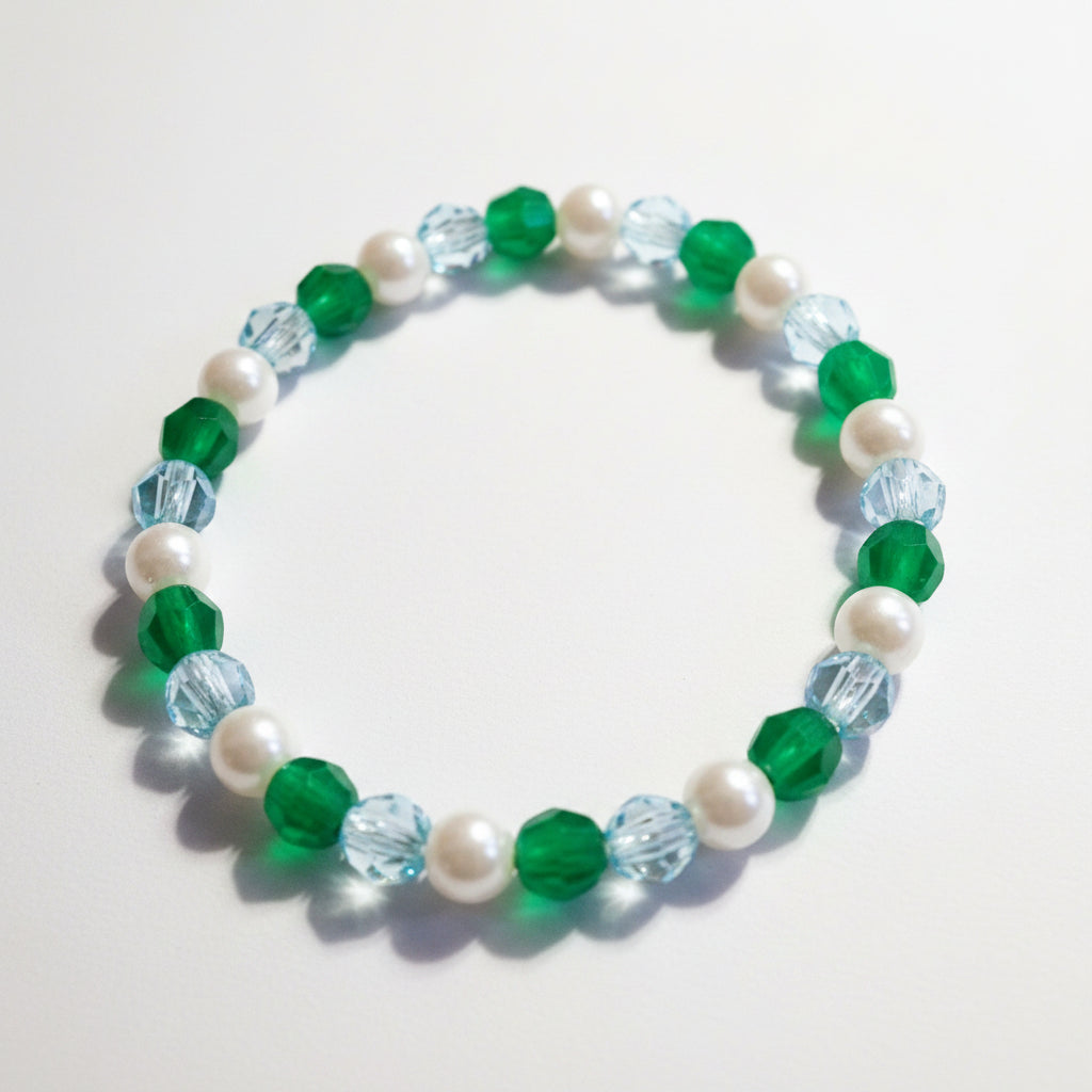 Beaded bracelet with green, white, and blue beads on a light background