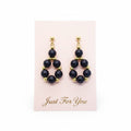 Pair of black beaded earrings with gold accents on a white card.