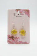 Yellow flower-shaped earrings on a 'sweet love' branded card with floral design.