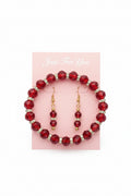 Red beaded bracelet with gold accents on a purple fabric background