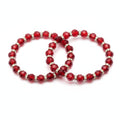 Red beaded bracelet with gold accents on a purple fabric background
