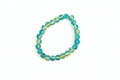 Beaded bracelet with blue and green beads on a marble surface