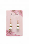 Pearl earrings on a 'Sweet Love' branded card with a purple and floral background