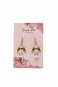 Angel wing earrings on a 'Sweet Love' branded card against a purple fabric background