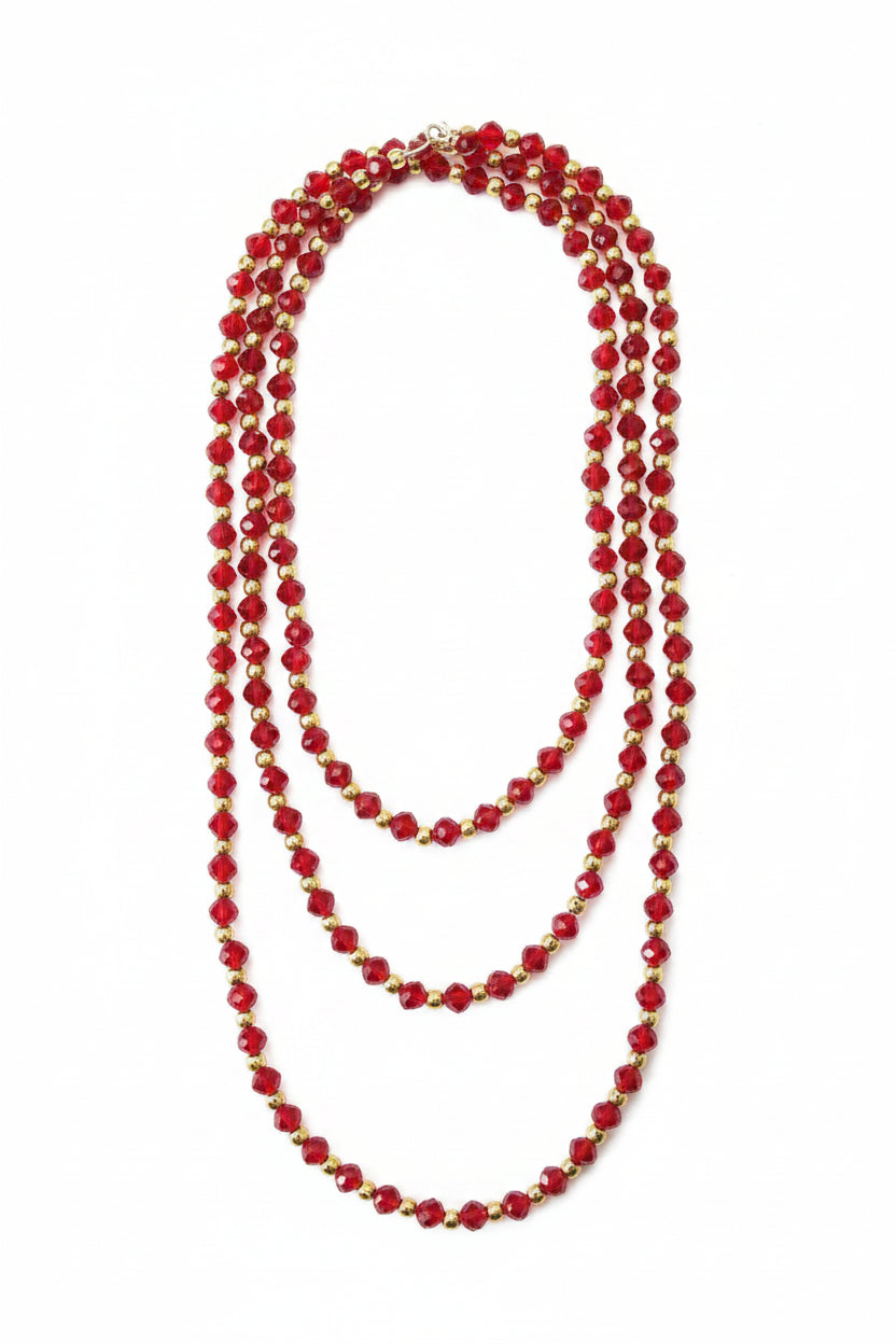 Red crystal beaded necklace with gold spacers on a textured white background